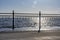 Wrought iron railing at the pier and shadows with sunlight and waves