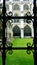 Wrought iron window of ancient church overlooking green grass of courtyard