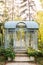 Wrought metal gazebo in summer garden. Flowers in pots near porch. Sofa in spring gazebo. Large iron blue gazebo for relax outdoor