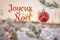 "Joyeux NoÃ«l" means "Merry Christmas" in French. Blurred background of beautiful Christmas tree in snow