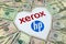 XEROX and HP logos on the paper brochure and dollar bills placed around in a shape of heart.