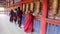 XIAHE, CHINA - AUGUST 24, 2018: People pass a row of praying wheels around Labrang Monastery in Xiahe town, Gansu