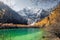 Xiannairi mountain on emerald lake with golden pine forest in autumn