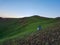 Xilinhot - A man sitting on a stone on a green hill in Xilinhot, Inner Mongolia and enjoys a sunset. He is wearing a cowboy hat