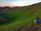 Xilinhot - A man sitting on a stone on a green hill in Xilinhot, Inner Mongolia and enjoys a sunset. He is wearing a cowboy hat