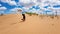 Xilinhot - A woman in shorts throwing sand above her head while sitting on a sand dune on Hunshandake Desert