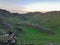 Xilinhot - A woman sitting on a stone on a green hill in Xilinhot, Inner Mongolia and enjoys a sunset. She is flipping her hair