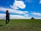 Xilinhot - A woman standing on a vast pasture in Xilinhot in Inner Mongolia. In the back there is a heap of stones (aobao)