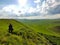 Xilinhot - A woman walking on a green hill in Xilinhot, Inner Mongolia. Endless grassland with a few wind turbines in the back