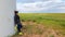 Xilinhot -A woman in yellow sneakers leaning against the pillar of a wind turbine on a vast grassland in Xilinhot, Inner Mongolia