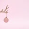 Xmas composition made of horns and a decorative Christmas pink bauble decoration on pastel pink background. New Year cretive