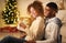 Xmas magic. Joyful black spouses opening Christmas gift together