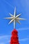 Xmas star on top of a Christmas tree against blue sky