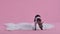 Xoloitzcuintle in a jumpsuit stands on a white fur blanket on a pink background. Soap bubbles fly around the pet, he