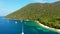 Yacht anchoring in crystal clear turquoise water in front of the tropical island, alternative lifestyle, living on a boat. Aerial