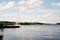 Yacht on blue peaceful lake on green forest and blue sky background