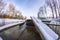 Yacht and jetty in a winter harbor covered in ice and snow, bridge and trees in the background. Winter