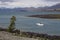 Yacht in Lake Tekapo with lupines blossom on the shore, New Zealand