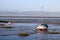 Yacht and other small boat on shore by Morecambe promenade at the side of Morecambe Bay, Lancashire, England with wiew across the