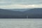 A yacht, a sailboat sailing on a lake with waves and dense gray thunderstorm cumulus clouds. White yacht riding