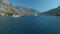 The yacht sails along the Bay of Kotor, behind it there are beautiful mountains and cozy little town