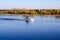 The yacht sails along the river along the autumn forest