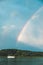 The yacht sails on the forest lake on the background of a rainbow