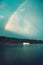 The yacht sails on the forest lake on the background of a rainbow