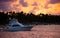 Yacht at sea against the sky, palm trees, clouds and sun at sunset