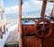 Yacht steering wheel and control panel. Ready to sea travel. Wooden deck interior of sailing boat. Ship on pier. Good