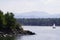 Yacht with a white sail is on the lake against the background of mountains and forests. view from camping, motorhomes, van life.