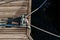 Yachting detail, rope and mooring double cross bollard on bridge in port of sailing. Wooden pier