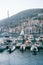 Yachts stand in rows along the piers in front of colorful houses. Lustica Bay Marina, Montenegro