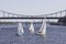 Yachts with white sails sailing on the river. Over the river bridge with pedestrians