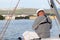 Yachtsman in marine clothing looking into the distance sitting on board a sailing yacht. Sea fishing from the ship. Peaceful state