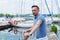 Yachtsman standing near of pier barrier with boats. Bearded man looking to far before journey near of yacht.