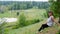 Yakut Asian girl sitting on a hillside smiling on the background of the taiga