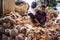 Yangon, Myanmar - December 31, 2019: A young man in longyi chopping coconuts