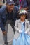 A Yankees fan and little girl in a blue dress and flowered bonnet pose for pictures at the Fifth Avenue Easter Parade.