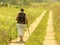 Yaslo, Poland - july 9 2018: Scandinavian / nordic walking. A woman in city clothes stroll through the summer`s grass in the rays