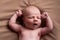 Yawning caucasian newborn baby yawning resting on brown blanket.