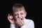 Yawning schoolboy with a red alarm clock in his hands. Morning concept. Black background