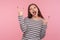 Yeah, awesome ! Portrait of excited rocker woman in striped sweatshirt showing rock and roll hand gesture