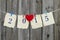 Year 2015 on antique paper with red heart hanging on clothesline by shabby wood fence