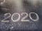 The year 2020 stamped on an old worn and scarred leather notebook macro photo angled view