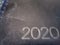 The year 2020 stamped on an old worn and scarred leather notebook macro photo angled view