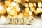 The year 2022 written on wooden cubes in gold luxury letters with shiny bokeh background, New Year celebration concept glitter