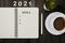 Yearly goals for 2021 - copybook, pen, cup of coffee and houseplant on wooden table