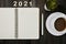 Yearly goals for 2021 - copybook, pen, cup of coffee and houseplant on wooden table