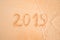 Years 2019 are inscribed on sandy beach on the yellow sand close-up. sea wave washes away the inscription 2019. The concept of